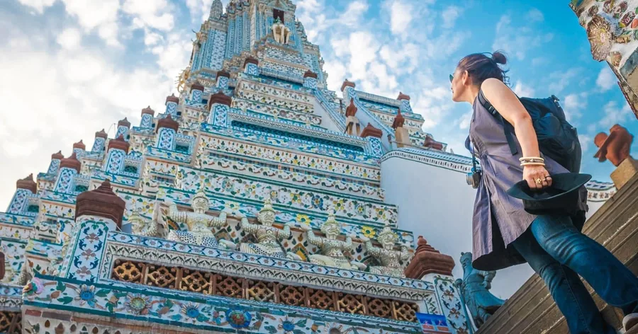 นักท่องเที่ยวกำลังปีนบันไดชันที่ประดับกระเบื้องเคลือบของพระปรางค์องค์ประธาน