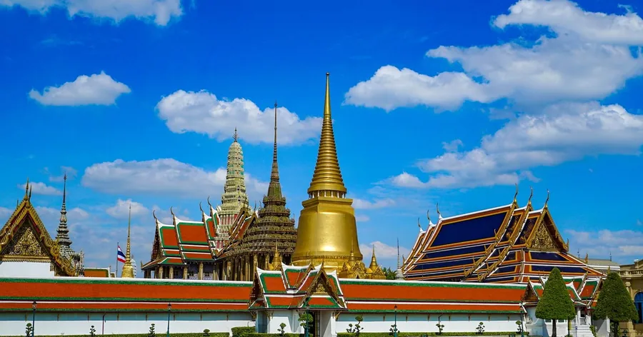 ยอดปราสาทปิดทองและหลังคามุงกระเบื้องของพระบรมมหาราชวังใต้ท้องฟ้าสีคราม